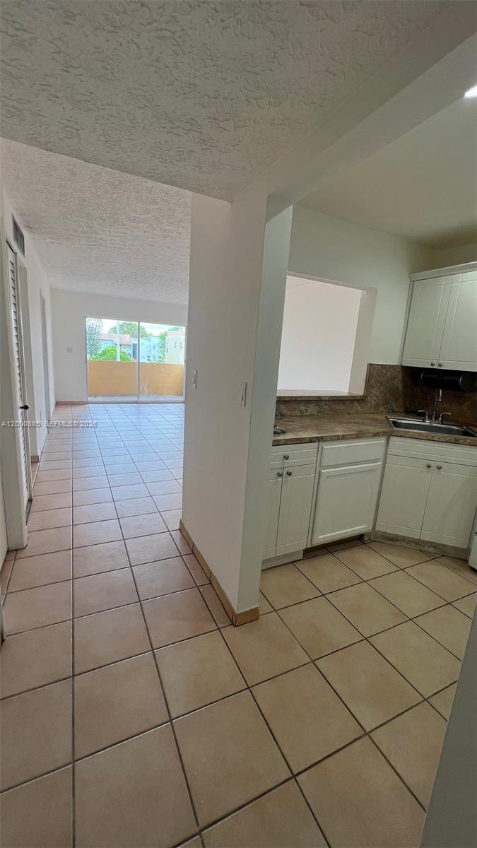 A tiled kitchen area opens into a living space with a balcony view — 6070 W 18th Ave # 323, Hialeah FL 33012, HIALEAH, FL