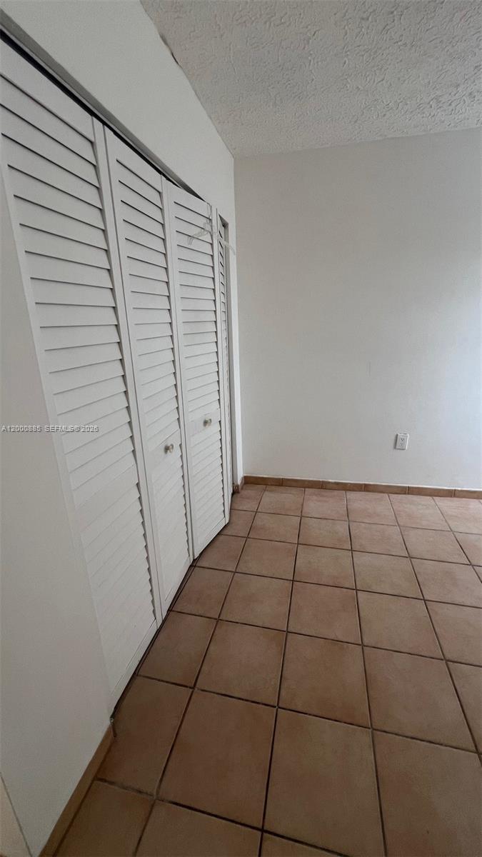 A room with white walls, tiled flooring, and a set of white louvered closet doors — 6070 W 18th Ave # 323, Hialeah FL 33012, HIALEAH, FL