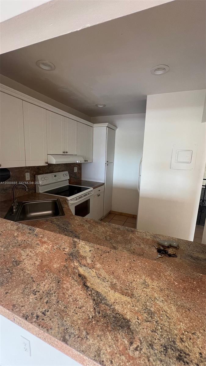A kitchen features white cabinets, a brown granite countertop, and a stainless steel sink — 6070 W 18th Ave # 323, Hialeah FL 33012, HIALEAH, FL