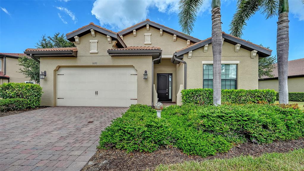 A single-story house with a beige stucco exterior, a two-car garage, and a paved driveway — 1051 BRADBERRY DRIVE, NOKOMIS, FL