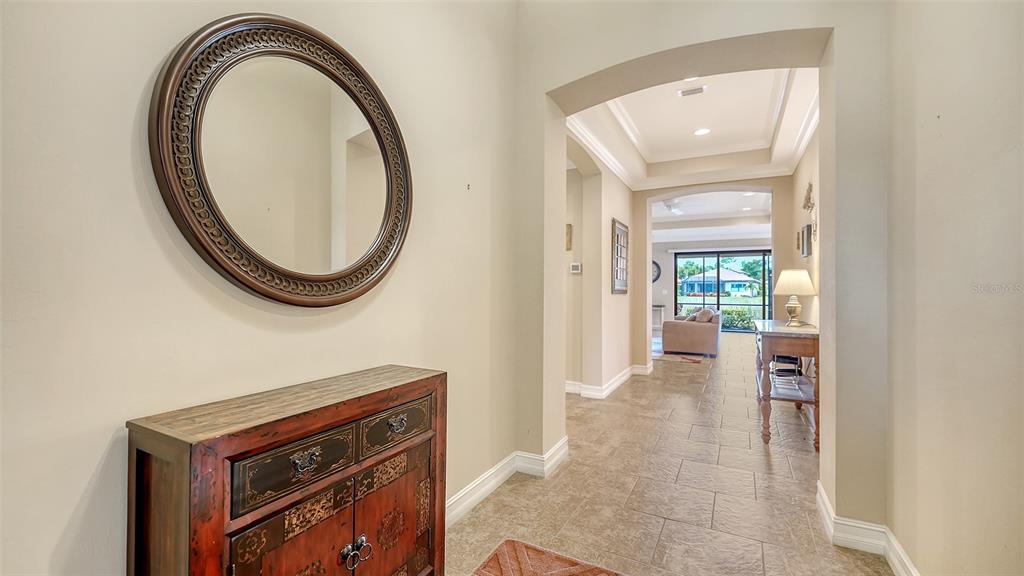 A foyer features a round mirror, a wooden cabinet, and a view into the living area — 1051 BRADBERRY DRIVE, NOKOMIS, FL