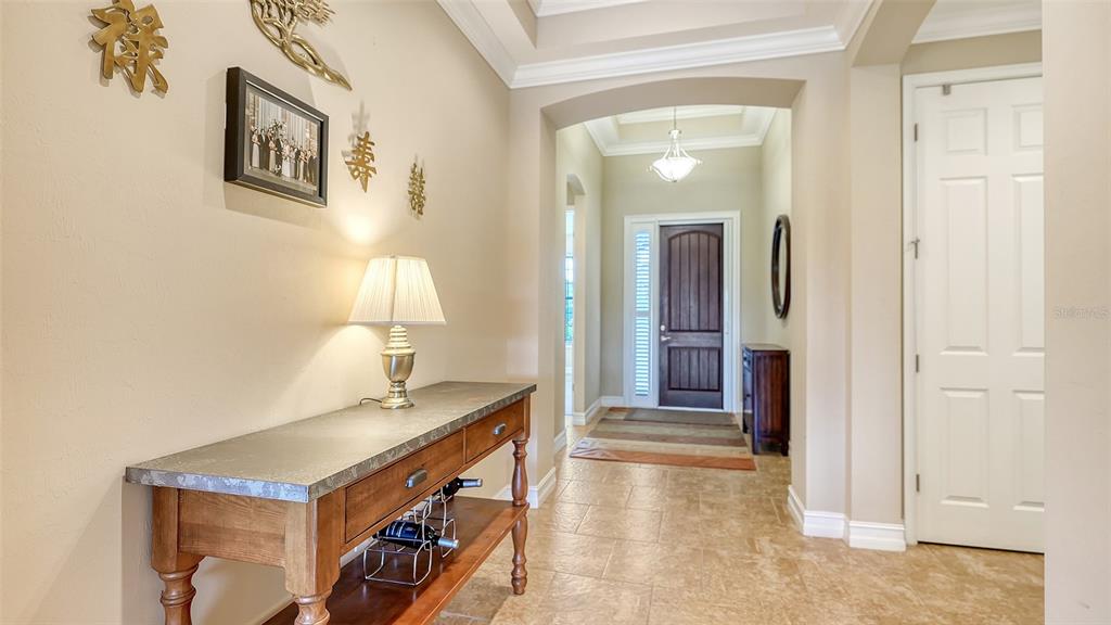 A foyer features a console table, tile flooring, and a dark wood front door — 1051 BRADBERRY DRIVE, NOKOMIS, FL