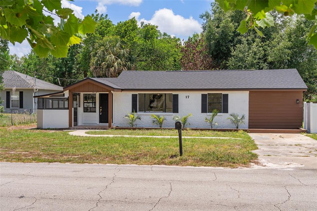 A single-story house with white stucco, brown trim, a dark roof, and a front porch — 17 PALMIRA ROAD, DEBARY, FL