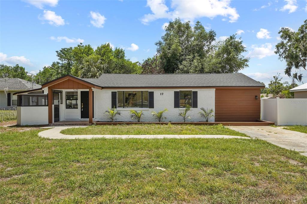A single-story house with white stucco, brown wood accents, and a concrete walkway — 17 PALMIRA ROAD, DEBARY, FL