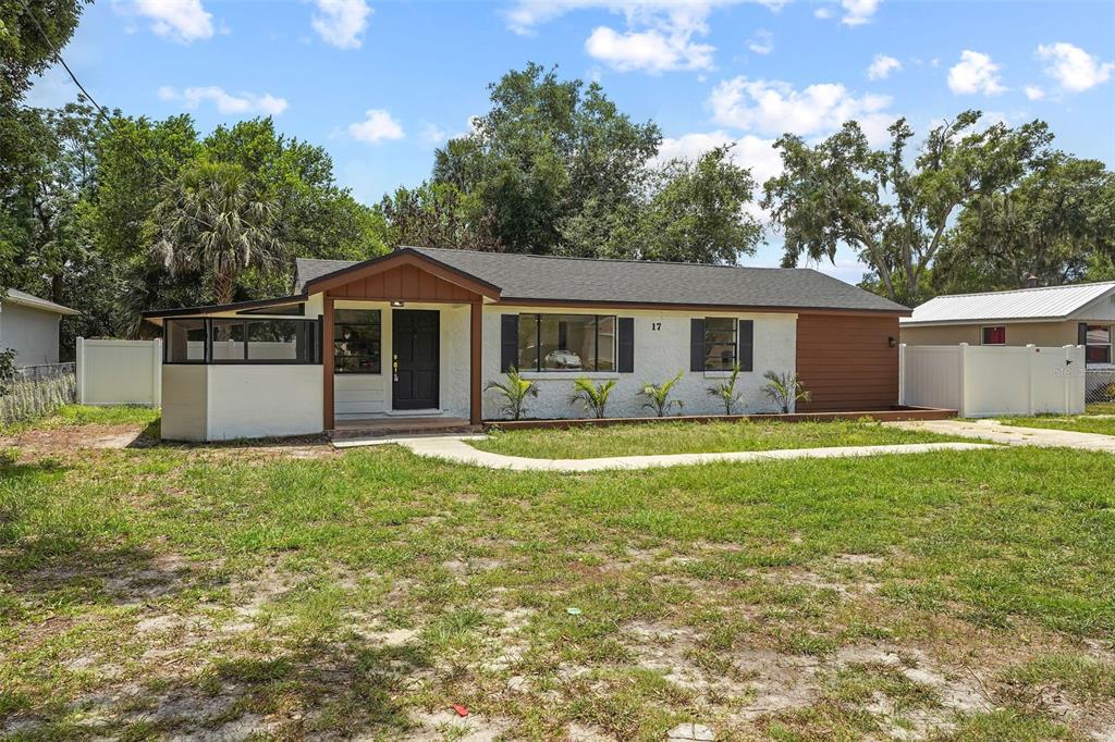 A single-story house with a white stucco facade, brown trim, and a front porch — 17 PALMIRA ROAD, DEBARY, FL