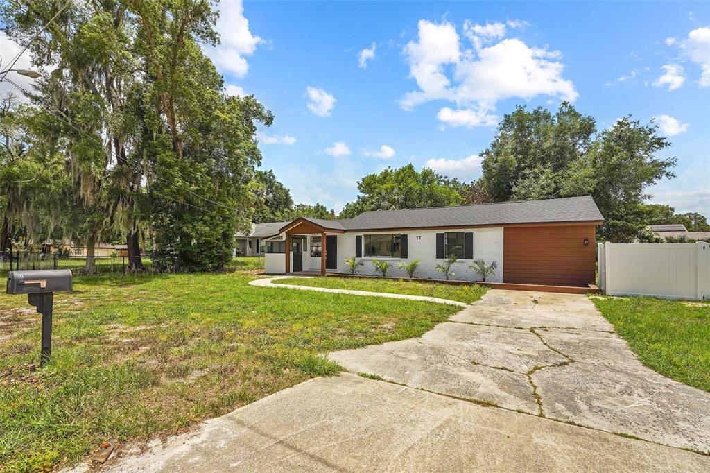 A single-story house with a white exterior, wood siding, and a concrete driveway — 17 PALMIRA ROAD, DEBARY, FL
