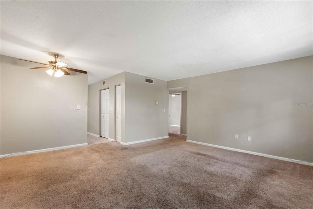 A carpeted living room features a ceiling fan and doorways leading to other interior spaces — 204 PINE TULIP COURT UNIT 201, TAMPA, FL
