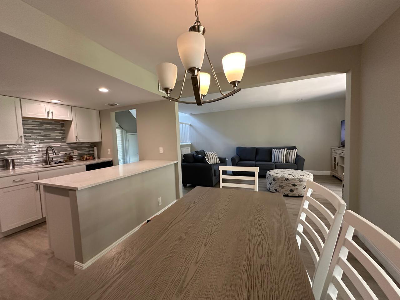 An open-concept dining area with a wooden table, white chairs, and a kitchen island — 7200 NW 2nd Avenue # 1520, Boca Raton FL 33487, BOCA RATON, FL