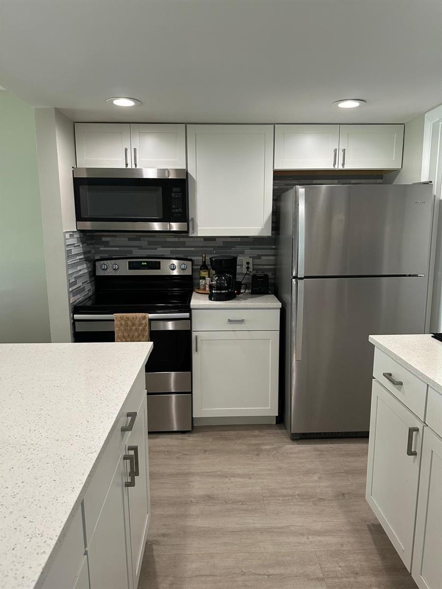 A kitchen features white cabinets, stainless steel appliances, a tiled backsplash, and light-colored countertops — 7200 NW 2nd Avenue # 1520, Boca Raton FL 33487, BOCA RATON, FL