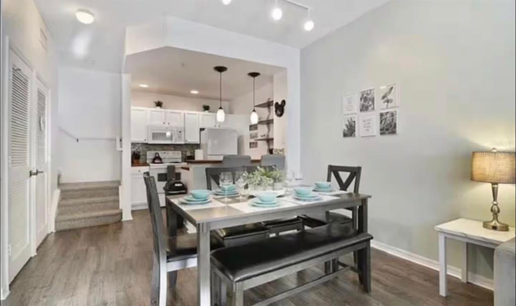 A dining area with a wooden table and bench sits in front of an open kitchen — 4560 E YELLOWGOLD ROAD APT 105, KISSIMMEE, FL