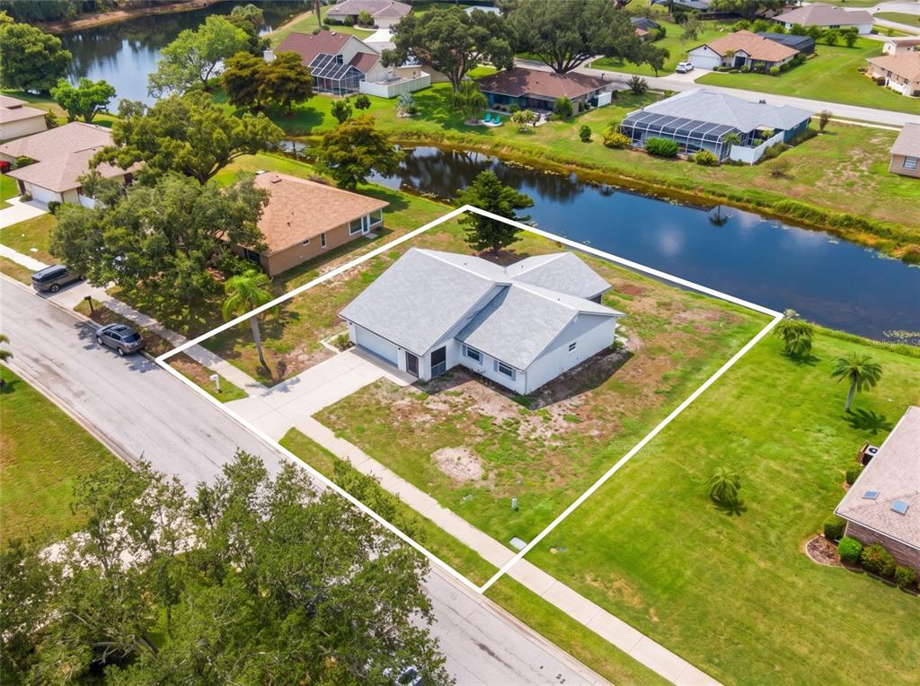 An aerial view shows a single-story house with a gray roof situated on a corner lot — 112 WOODINGHAM DRIVE, VENICE, FL