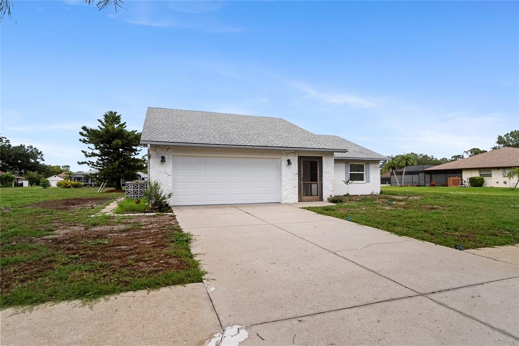 A single-story house with a white garage, stone facade, and a concrete driveway — 112 WOODINGHAM DRIVE, VENICE, FL