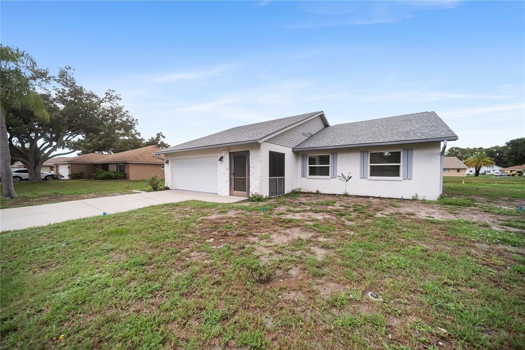 A single-story house with a white stucco exterior, a gray shingled roof, and a driveway — 112 WOODINGHAM DRIVE, VENICE, FL