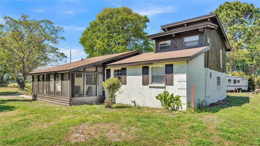 A two-story house with a white stucco exterior, brown wood siding, and a screened porch — 503 MARIANNA ROAD, AUBURNDALE, FL