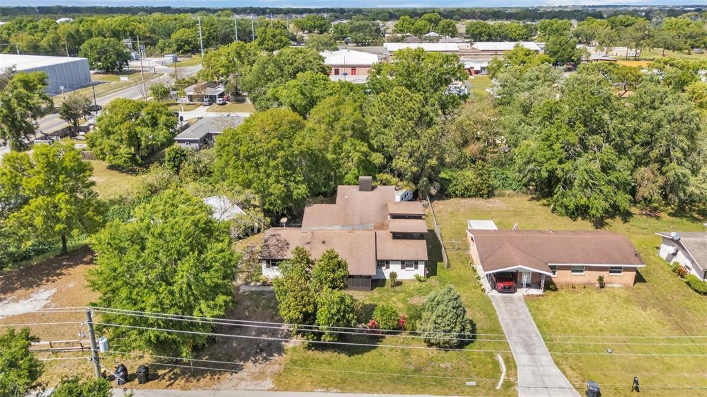 An aerial view shows two adjacent houses with brown roofs surrounded by many green trees — 503 MARIANNA ROAD, AUBURNDALE, FL