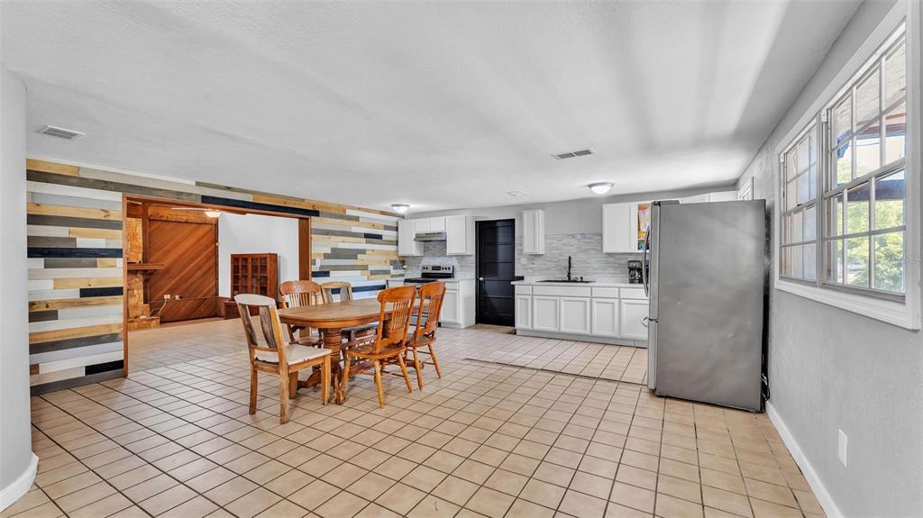 A kitchen and dining area with tile floors, white cabinets, and a wood-paneled accent wall — 503 MARIANNA ROAD, AUBURNDALE, FL
