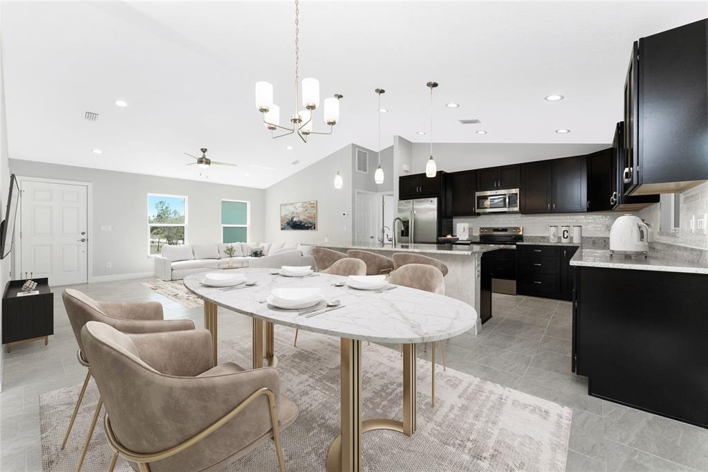 An open-concept kitchen and dining area features dark cabinetry, a marble-topped table, and tile flooring — 1453 LINDSAY AVENUE, NORTH PORT, FL