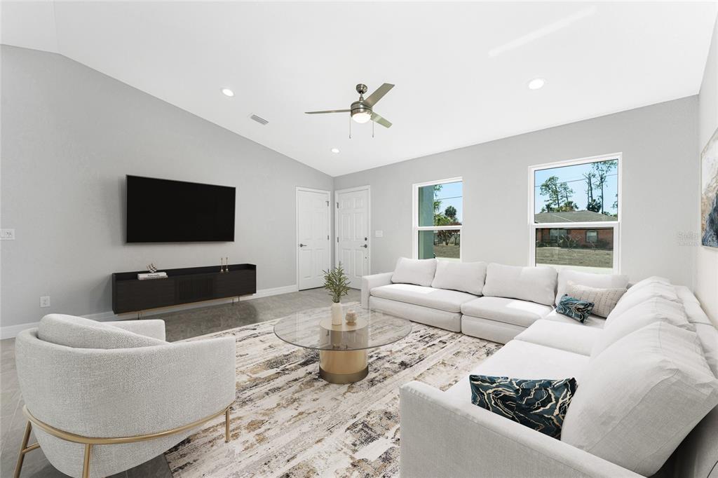 A living room features a vaulted ceiling, a sectional sofa, a round coffee table, and television — 1453 LINDSAY AVENUE, NORTH PORT, FL