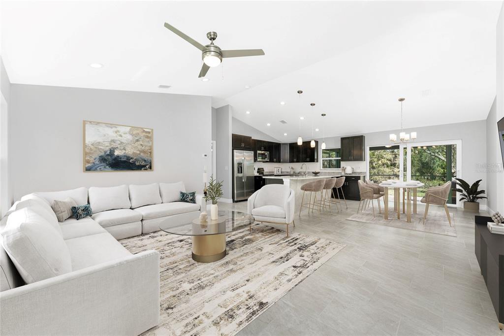 An open-concept living room and kitchen featuring a white sectional, dining area, and dark cabinetry — 1453 LINDSAY AVENUE, NORTH PORT, FL