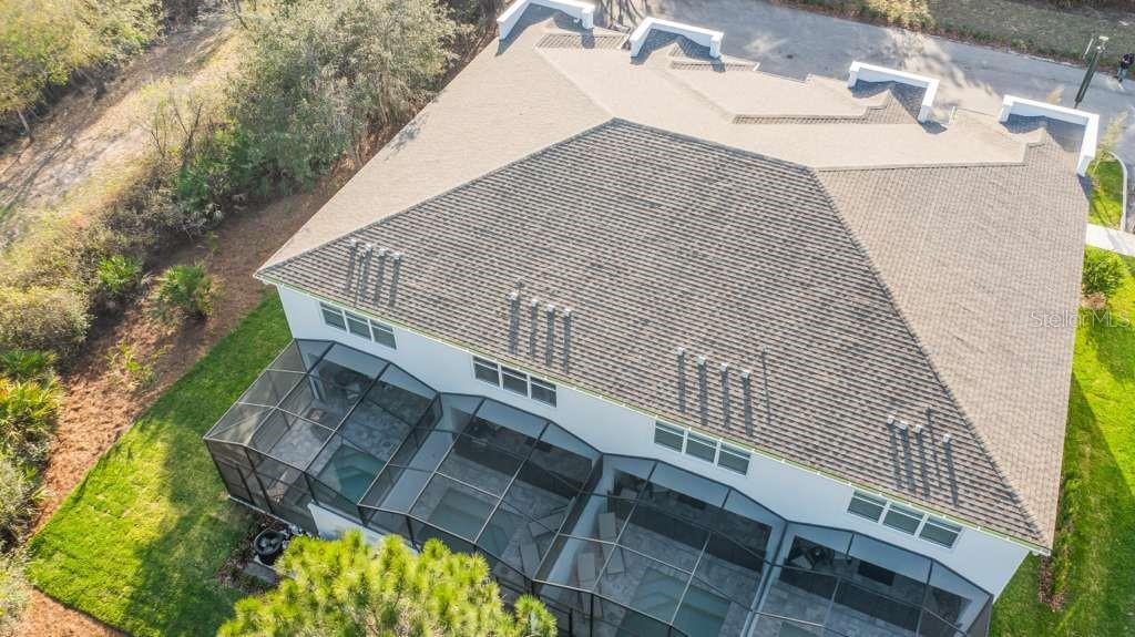 An aerial view of a house with a shingled roof and a screened-in pool area — 17102 BLESSING DRIVE, CLERMONT, FL