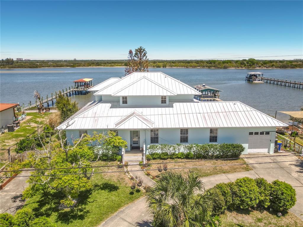 An aerial view of a light blue house with a white metal roof near water — 1205 S RIVERSIDE DRIVE, EDGEWATER, FL