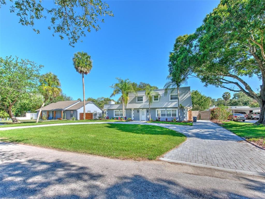 A two-story gray house with a paved driveway and palm trees sits on a lawn — 4711 W SAN RAFAEL STREET, TAMPA, FL