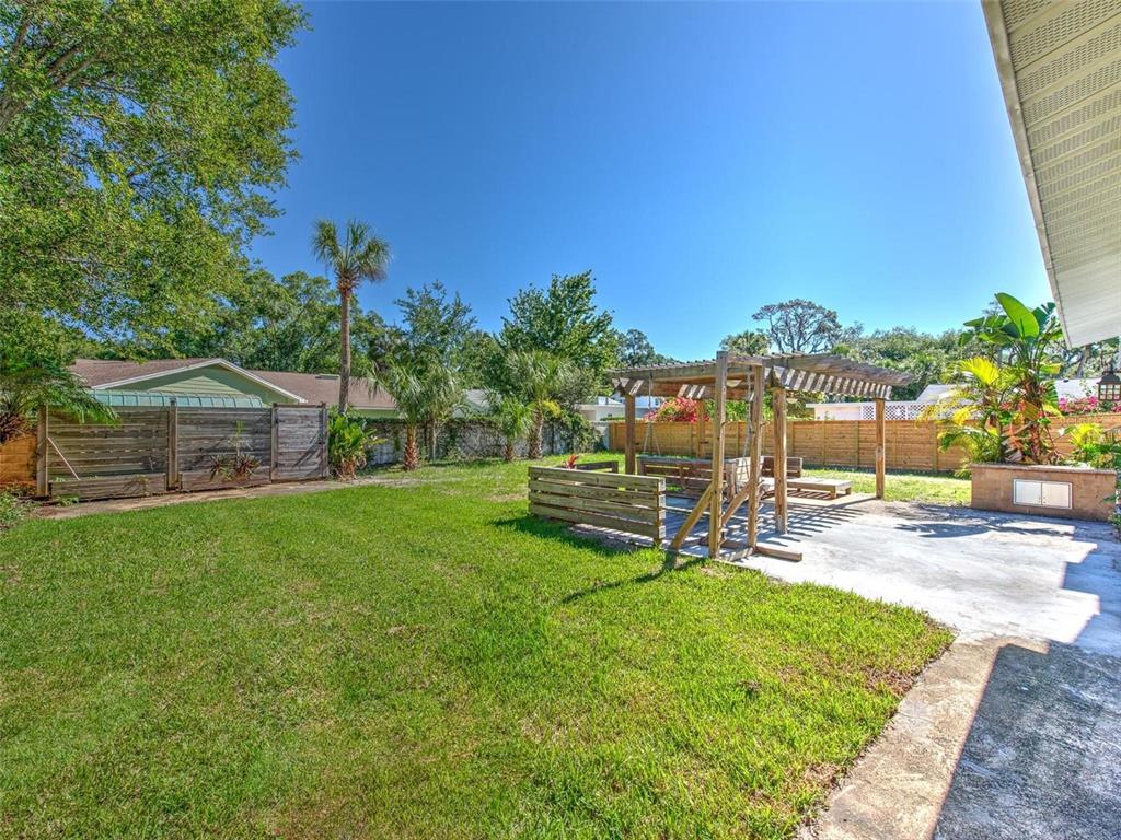 A backyard features a concrete patio, a wooden pergola, and a fenced lawn area — 4711 W SAN RAFAEL STREET, TAMPA, FL