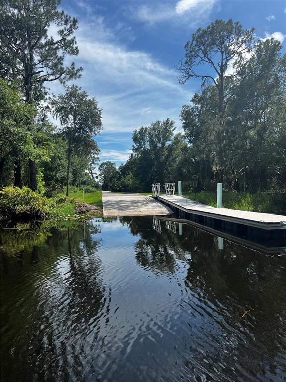A concrete boat ramp leads into a calm body of water beside a floating dock — 3412 LAKE DIANE RD #67, TAVARES, FL