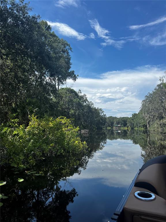 A view from a boat looking down a calm, tree-lined river under a blue sky — 3412 LAKE DIANE RD #67, TAVARES, FL