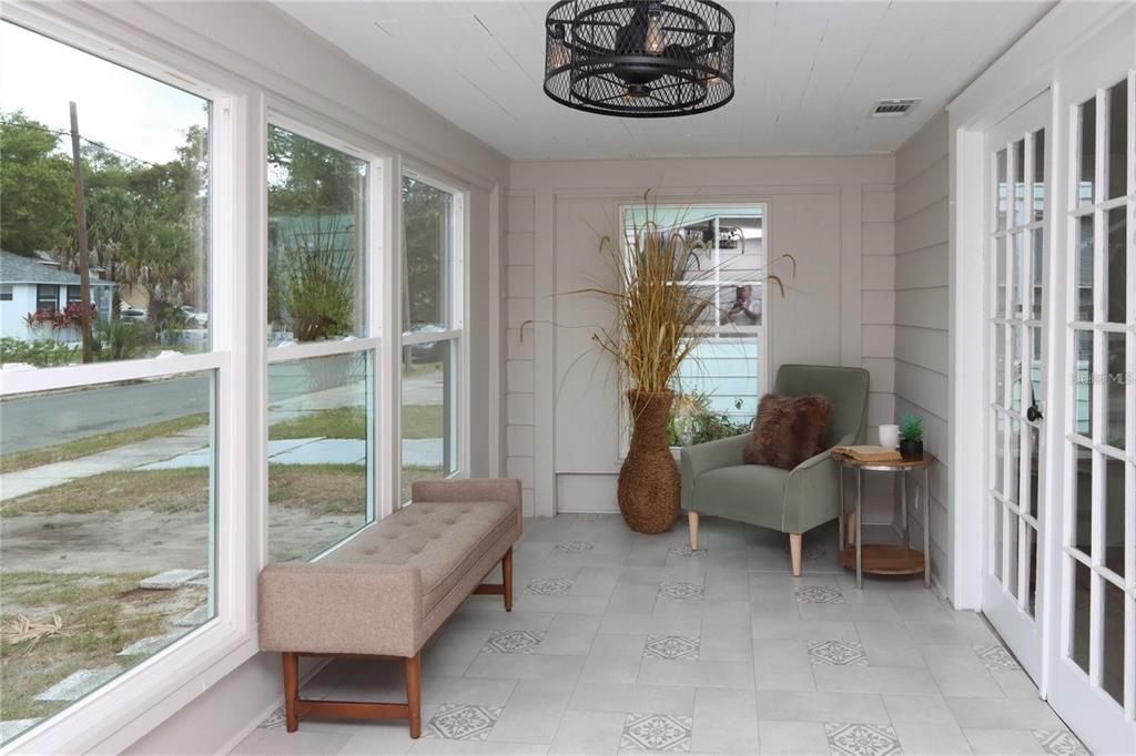 A sunroom with gray tiled floors, a tufted bench, an armchair, and a ceiling fan — 1532 13TH STREET S, ST PETERSBURG, FL