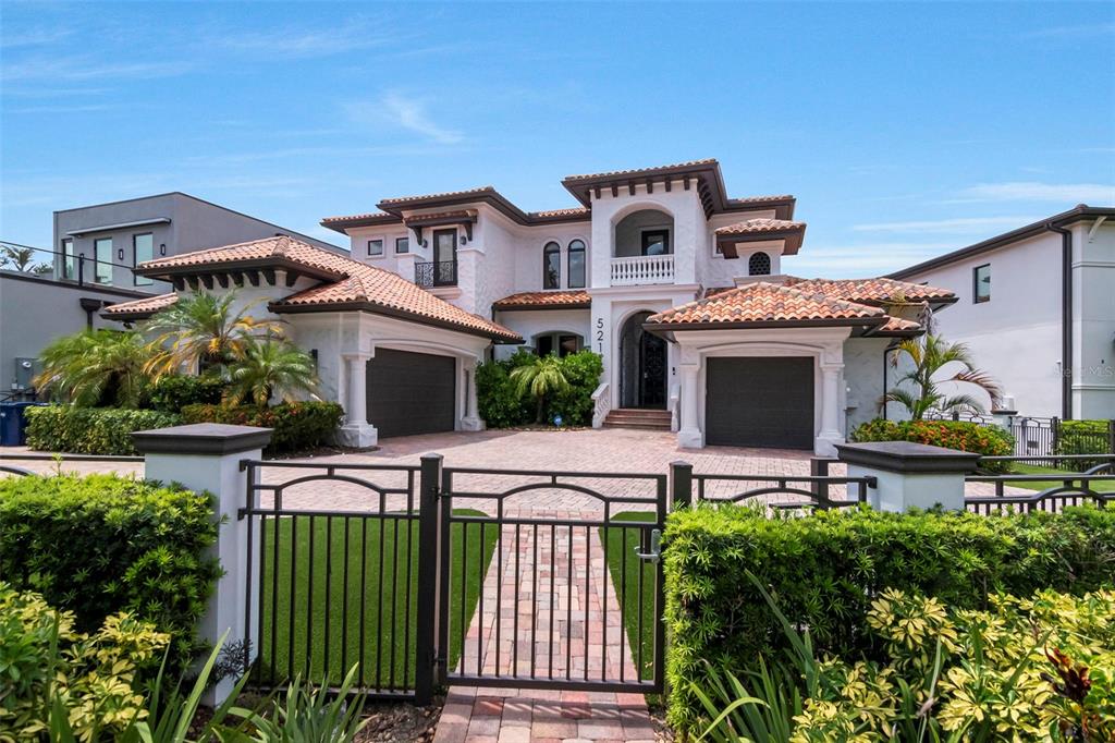 A two-story Mediterranean-style house with a tile roof, two garages, and a gated front entrance — 5211 W NEPTUNE WAY, TAMPA, FL