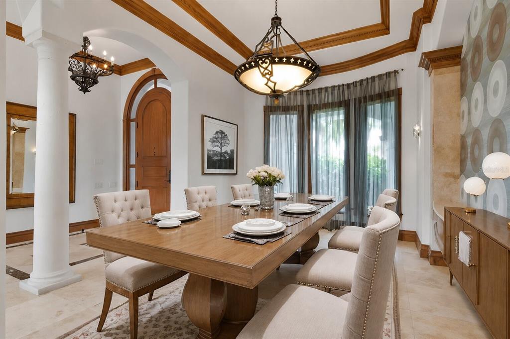 A formal dining room features a wooden table, tufted chairs, a chandelier, and arched doorways — 5211 W NEPTUNE WAY, TAMPA, FL