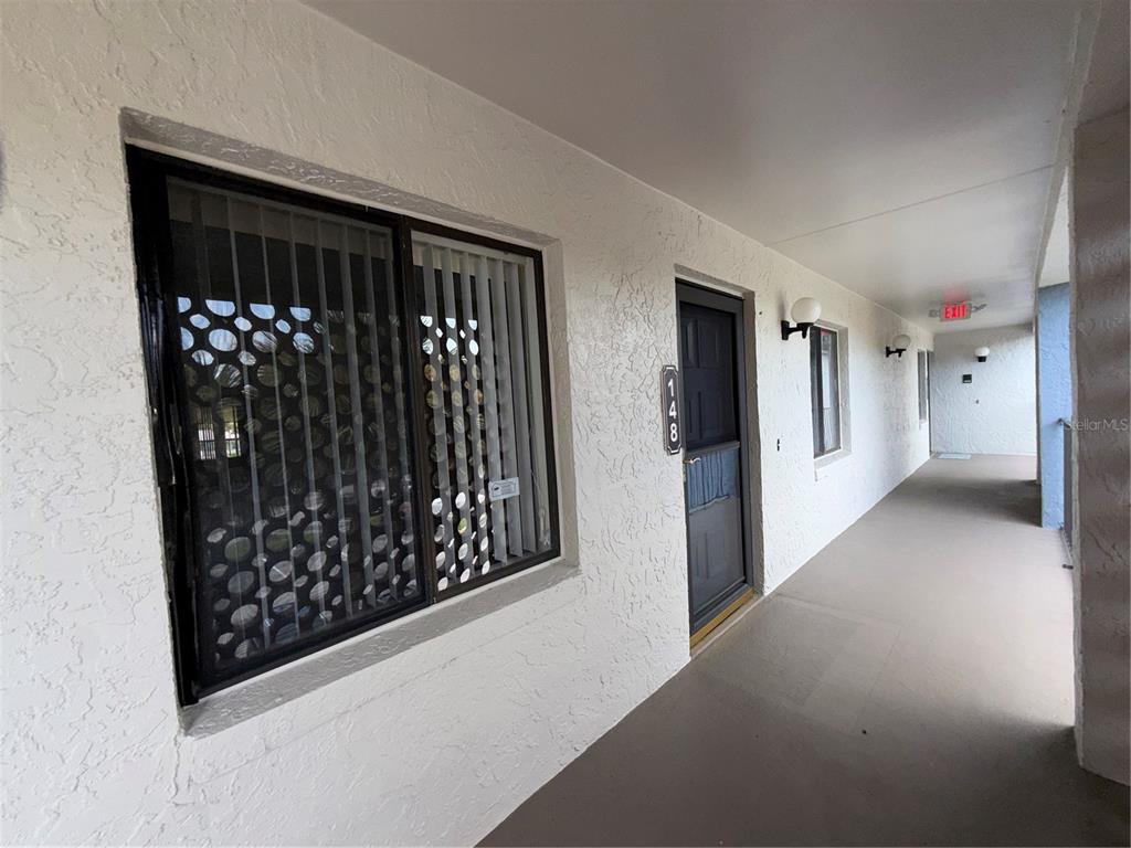 A covered exterior walkway leads to a front door numbered 148 with a large window — 15 ESCONDIDO COURT UNIT 148, ALTAMONTE SPRINGS, FL