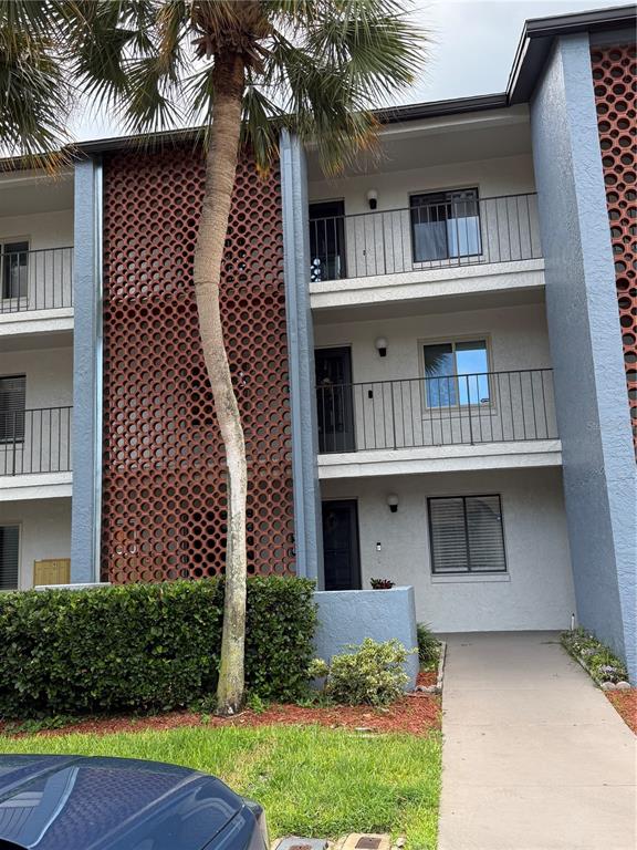A three-story apartment building exterior features decorative brown lattice screens and a palm tree — 15 ESCONDIDO COURT UNIT 148, ALTAMONTE SPRINGS, FL
