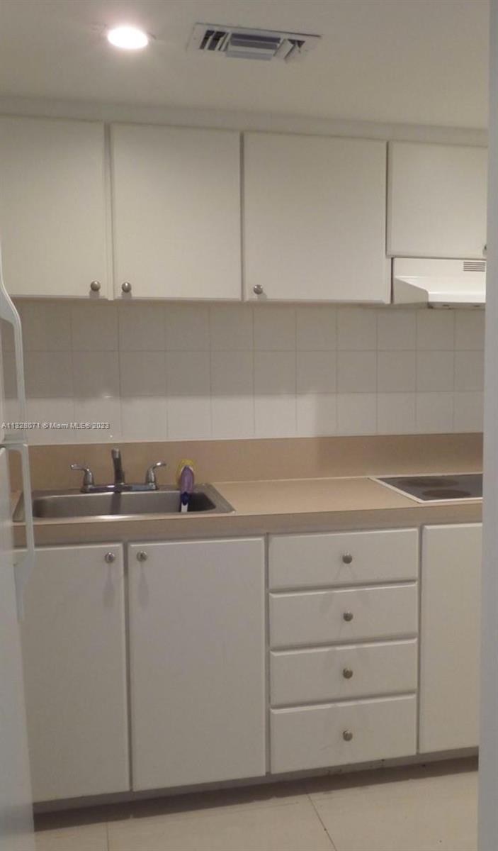 A kitchen features white cabinets, a stainless steel sink, and a tiled backsplash — 1000 West Ave # 1032, Miami Beach FL 33139, MIAMI BEACH, FL