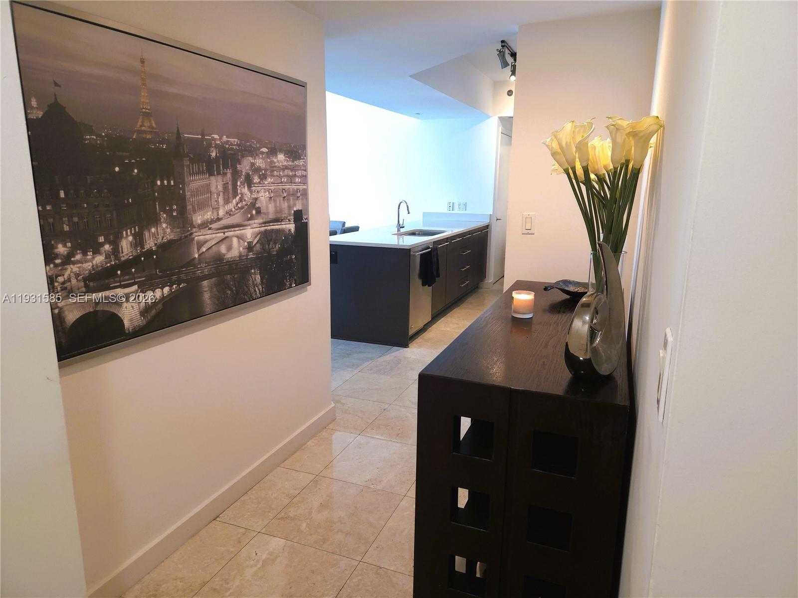 A hallway with a large Paris wall print leads to a kitchen with dark cabinetry — 500 Brickell Ave # 3105, Miami FL 33131, MIAMI, FL