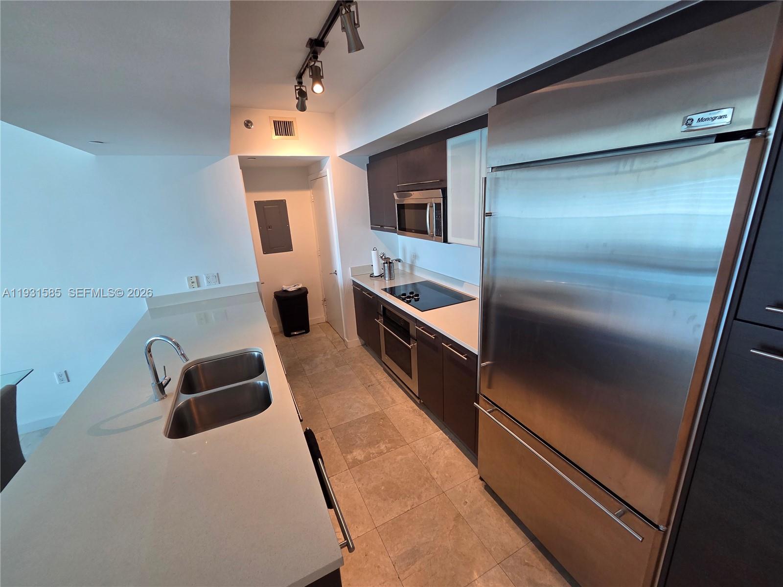 A modern kitchen features stainless steel appliances, dark cabinetry, and a light-colored stone countertop — 500 Brickell Ave # 3105, Miami FL 33131, MIAMI, FL