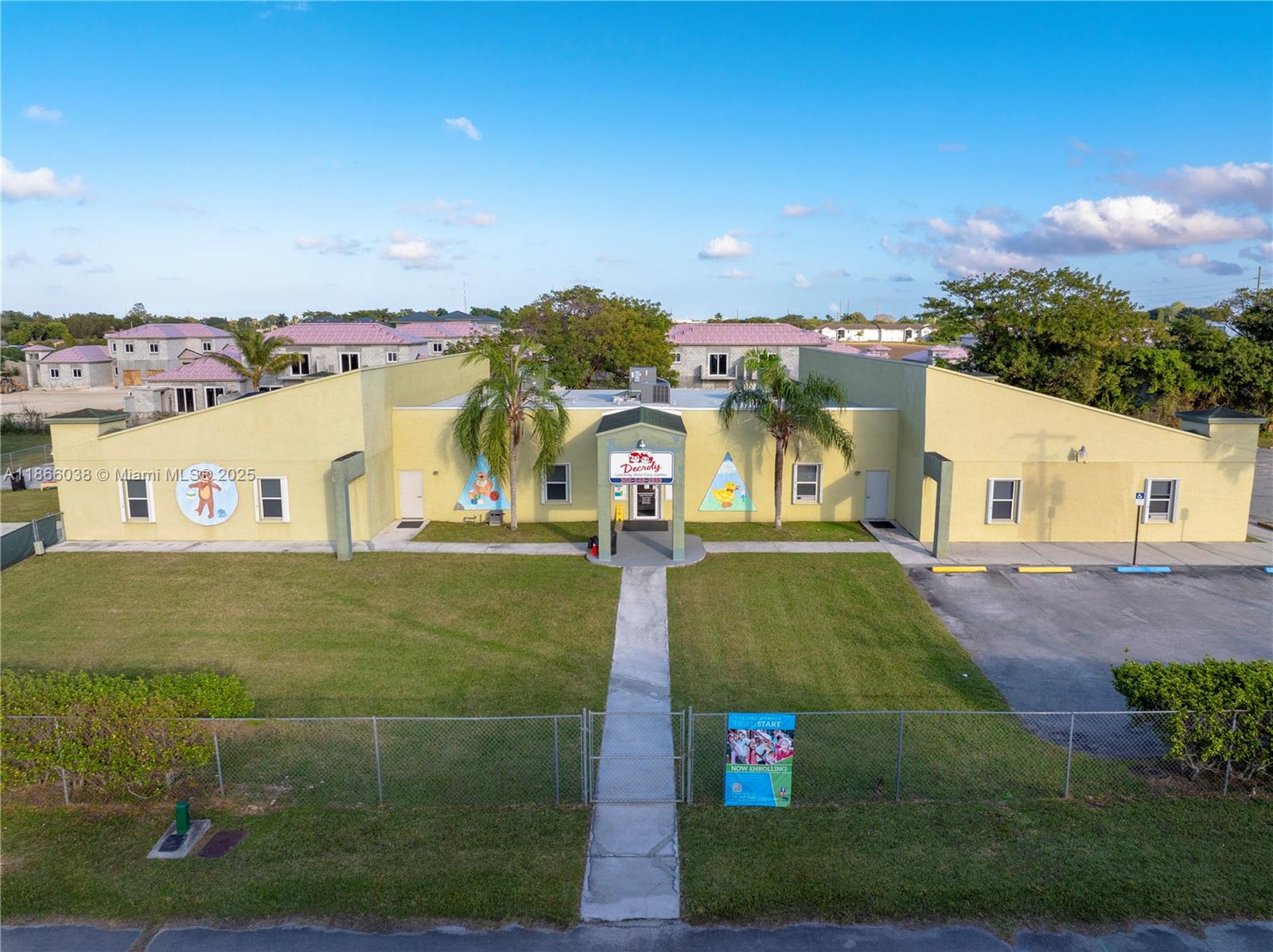 An aerial view shows a yellow, single-story daycare building with a central entrance and lawn — 1200 NE 8th St, Homestead FL 33033, HOMESTEAD, FL