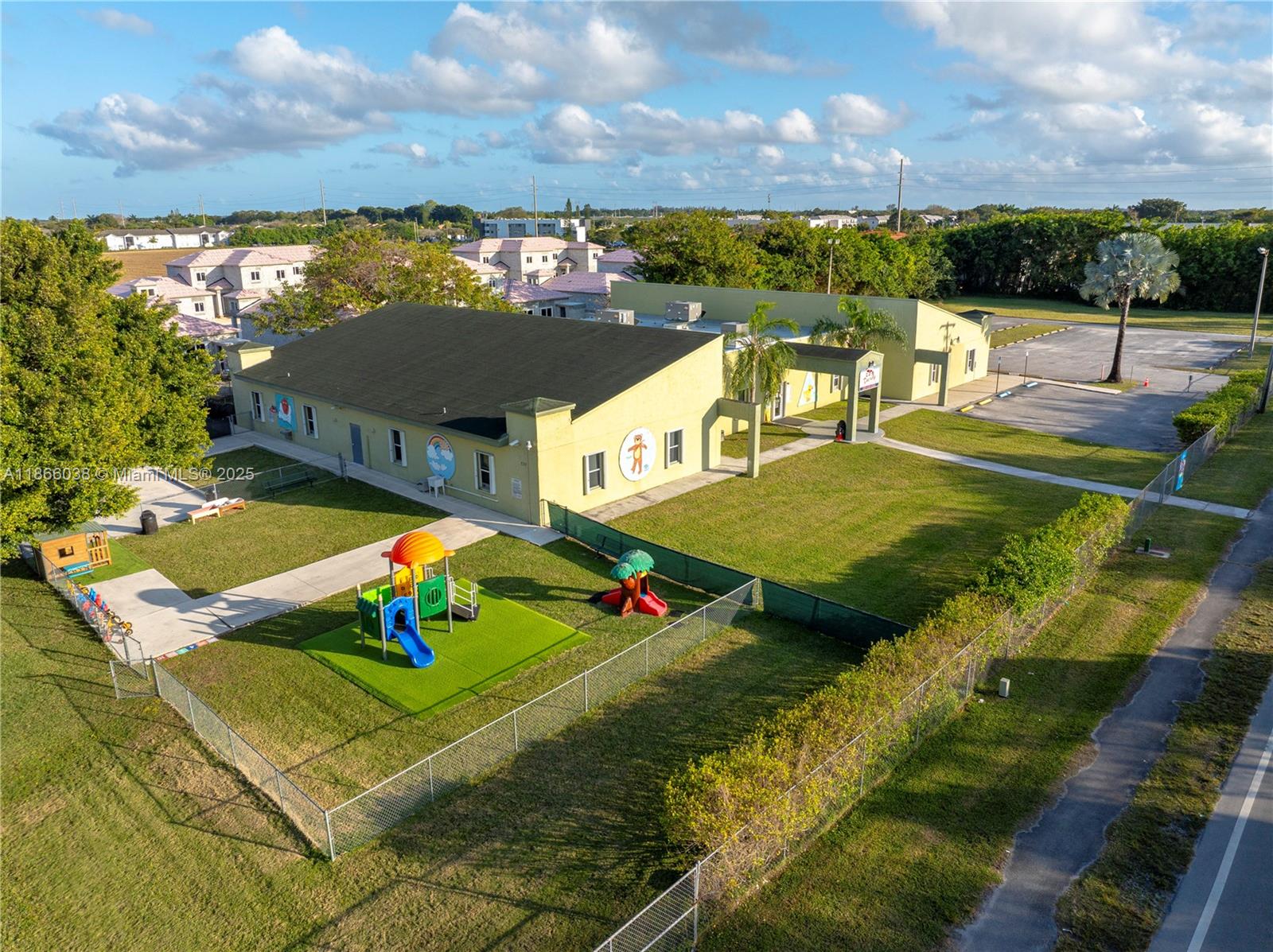 An aerial view shows a yellow building with a playground and parking lot — 1200 NE 8th St, Homestead FL 33033, HOMESTEAD, FL
