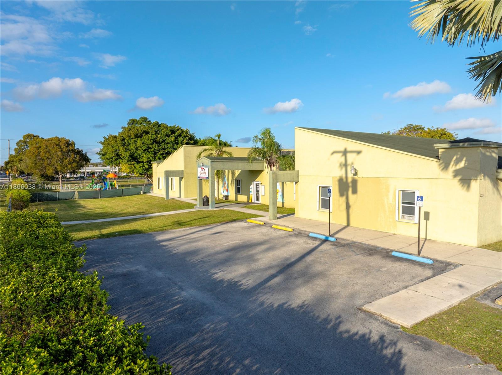 A yellow one-story building with a parking lot and a playground in the background — 1200 NE 8th St, Homestead FL 33033, HOMESTEAD, FL