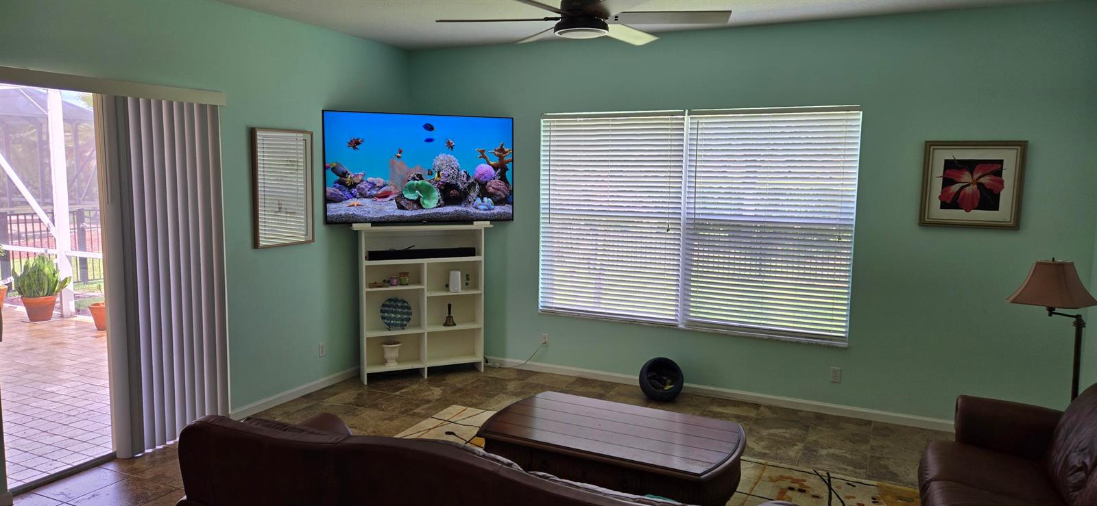 A living room with light green walls, a wall-mounted television, and a sliding glass door — 607 Tangelo Circle SW, Vero Beach FL 32968, VERO BEACH, FL