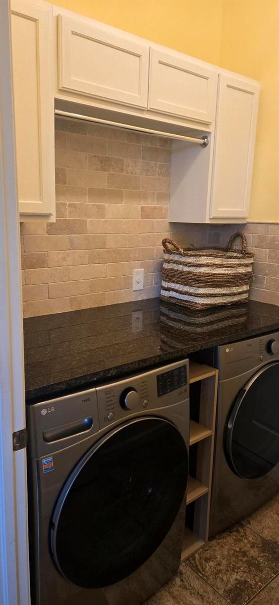 A laundry room features white cabinets, a dark granite countertop, and a light stone backsplash — 607 Tangelo Circle SW, Vero Beach FL 32968, VERO BEACH, FL
