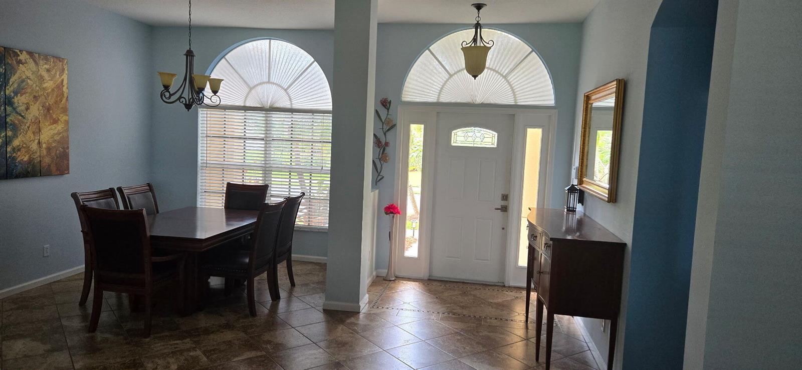 A dining area and entryway feature tile floors, arched windows, and a white front door — 607 Tangelo Circle SW, Vero Beach FL 32968, VERO BEACH, FL
