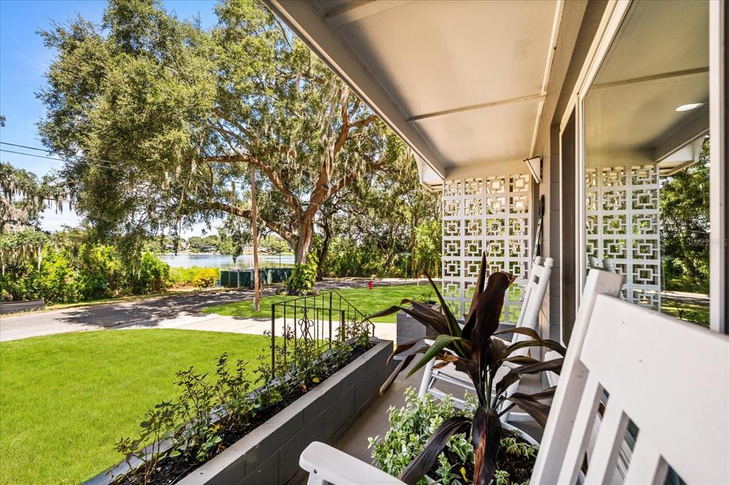 A covered front porch features a rocking chair, a planter, and a view of a lake — 1210 E CAROLINE STREET, TAVARES, FL