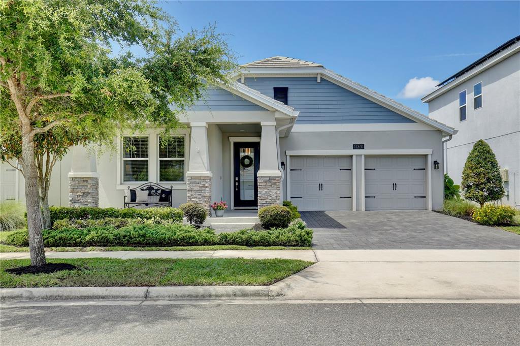 A single-story house with a blue-accented exterior, stone columns, and a two-car garage — 11341 SATIRE STREET, ORLANDO, FL