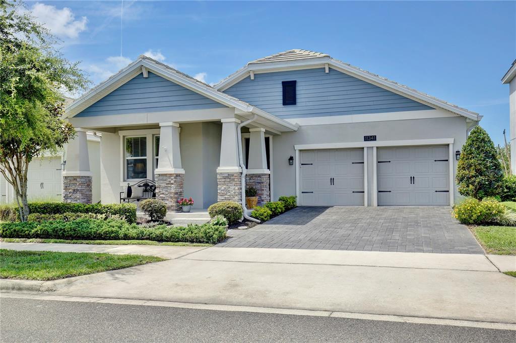 A single-story house with blue siding, stone accents, and a two-car garage — 11341 SATIRE STREET, ORLANDO, FL