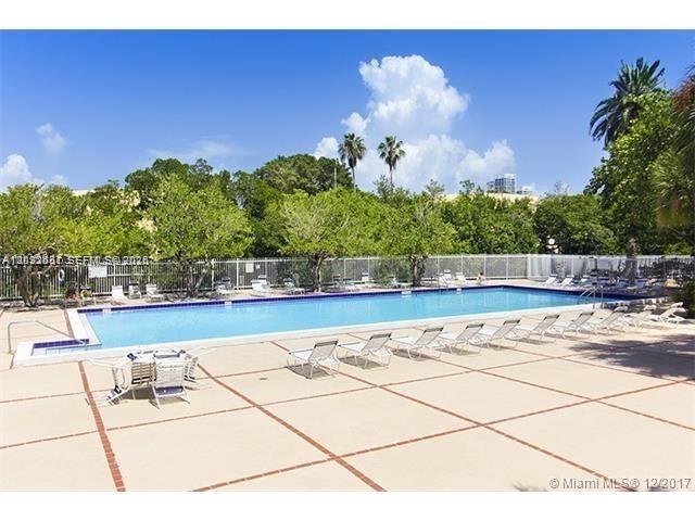 An empty room features light wood flooring, white walls, and large windows with tree views — 7441 Wayne Ave # 2O, Miami Beach FL 33141, MIAMI BEACH, FL