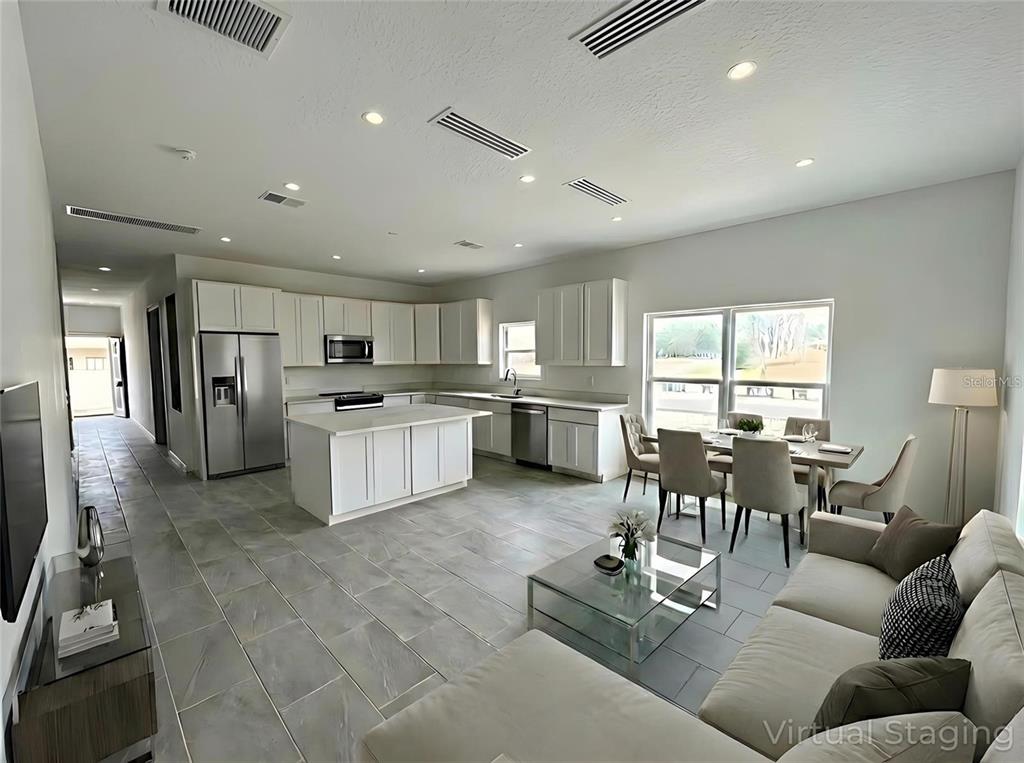 An open-concept kitchen and living area features white cabinetry, a central island, and tile flooring — 1405 W 14TH STREET, SANFORD, FL