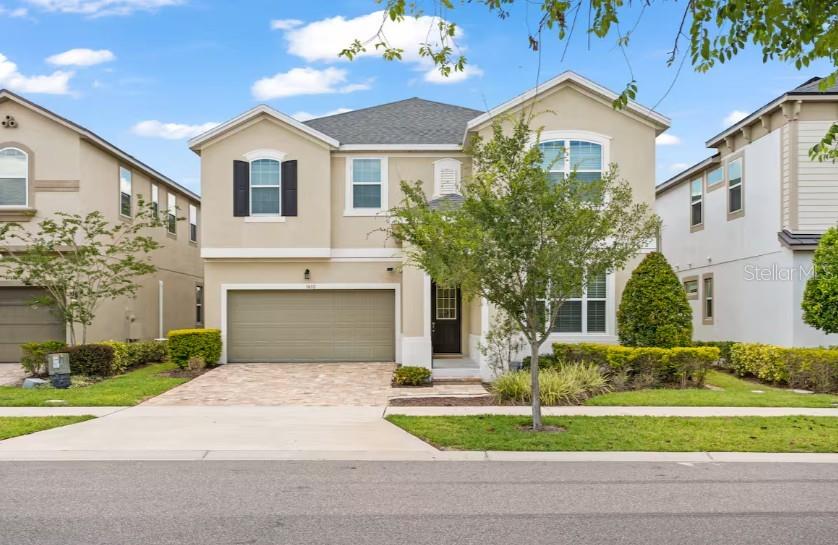 A two-story suburban house with a beige stucco exterior, a two-car garage, and landscaping — 1632 NASSAU POINT TRAIL, KISSIMMEE, FL