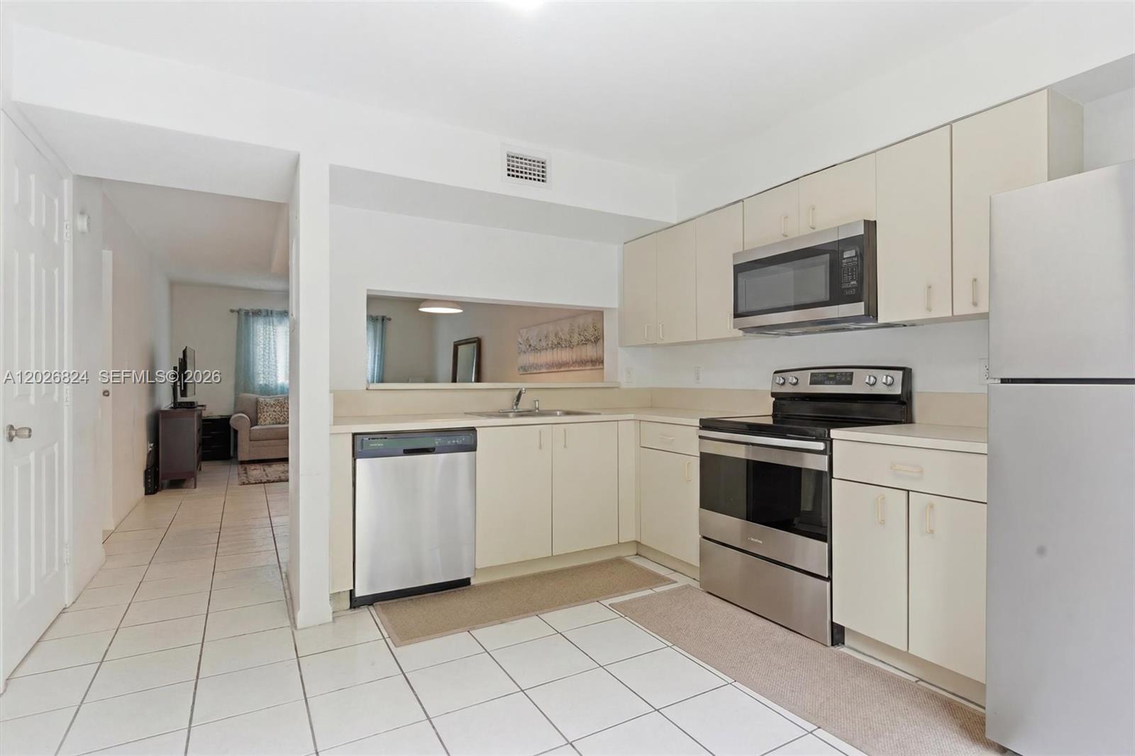 A kitchen features white cabinets, stainless steel appliances, and light-colored tile flooring — 8240 SW 149th Ct # 201, Miami FL 33193, MIAMI, FL